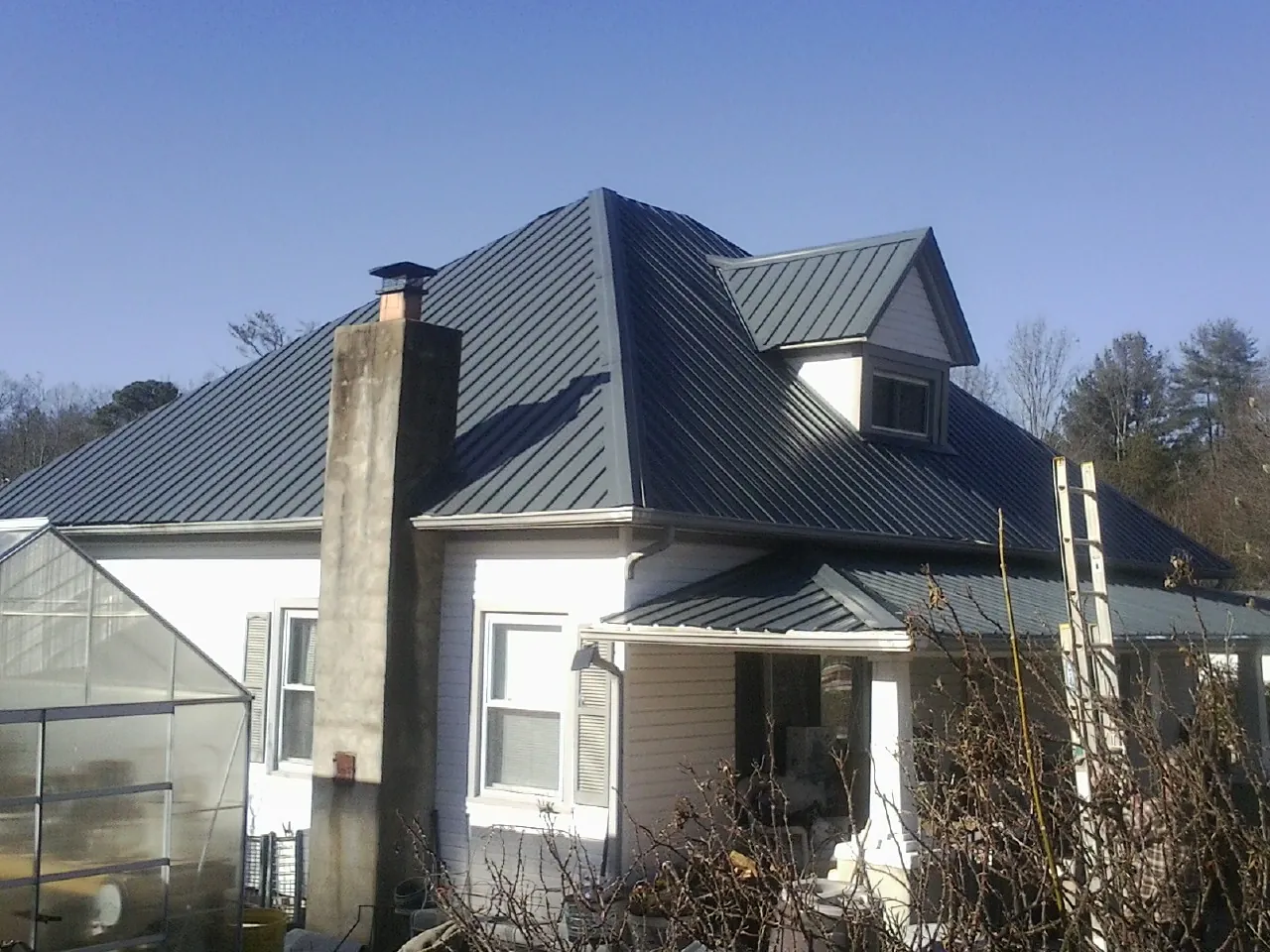 Dark blue standing seam metal roof on a white farmhouse with dormer — Slate & Tile Roof Repair by Roofing Brothers in Mc Connellsburg