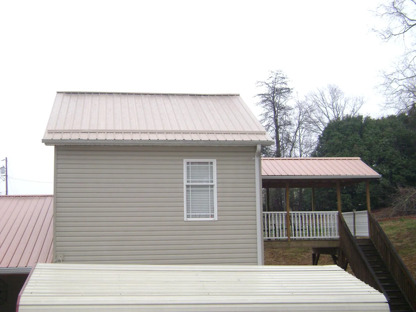 Tan metal roofs on a two story addition and attached porch, from a Roof Replacement job in Mc Connellsburg