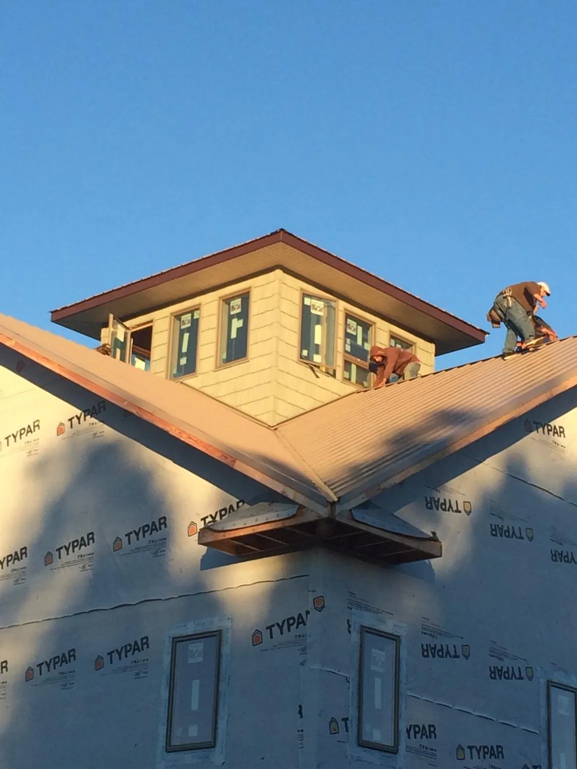 Roofers working around a rooftop cupola on a new metal roof at sunset — Roof Waterproofing in Mc Connellsburg by Roofing Brothers
